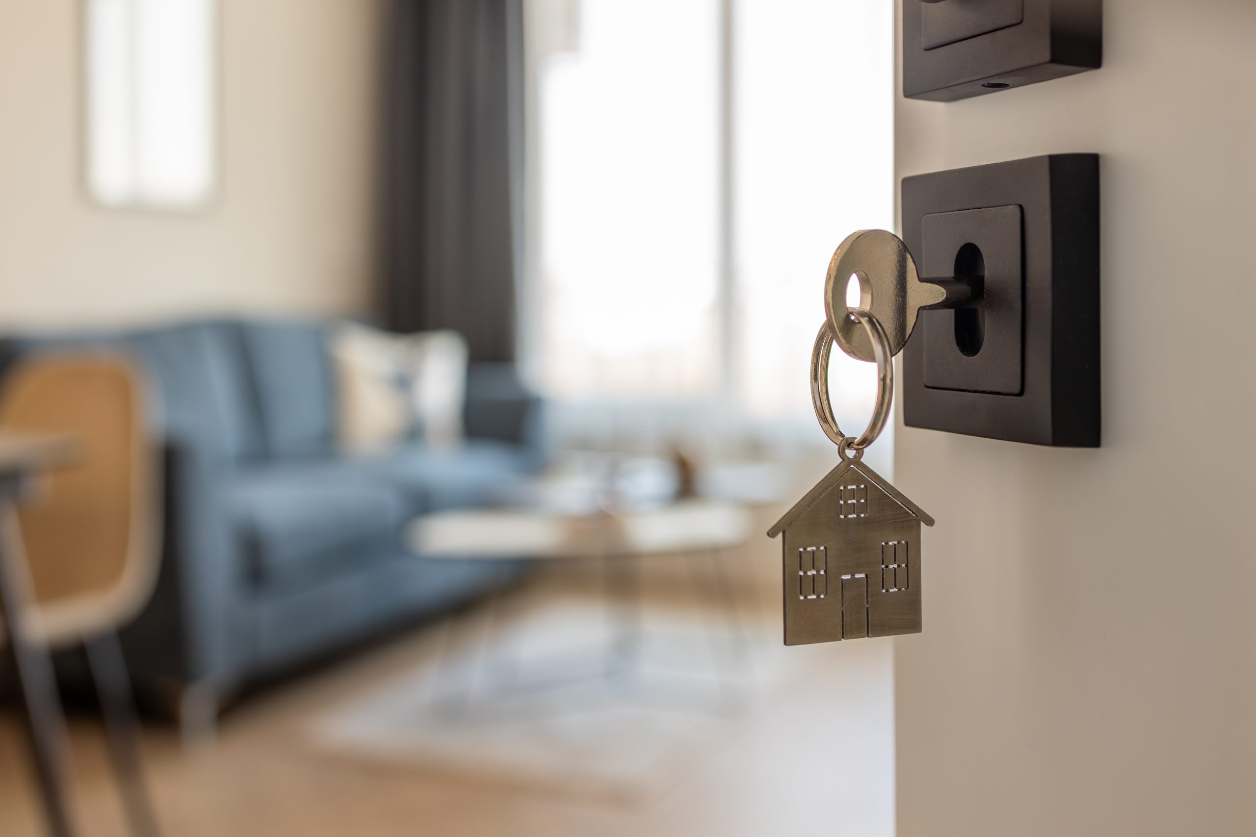 porte qui s'ouvre sur une pièce avec dans la sérrure une clé et un porte clé en forme de maison